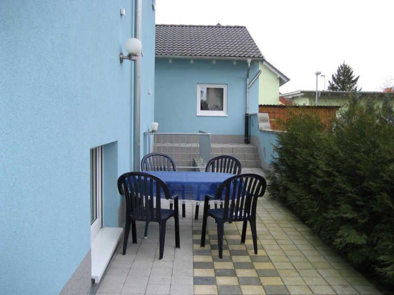 einen Tisch und Stühle auf einer Terrasse mit einem blauen Haus in der Unterkunft Gästezimmer Sieg in Rust