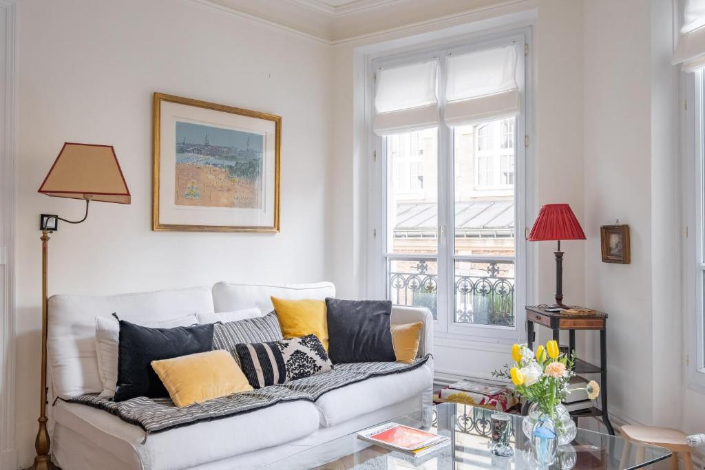 un salon avec un canapé blanc et une table en verre dans l'établissement Veeve - Honeybee Soul, à Paris