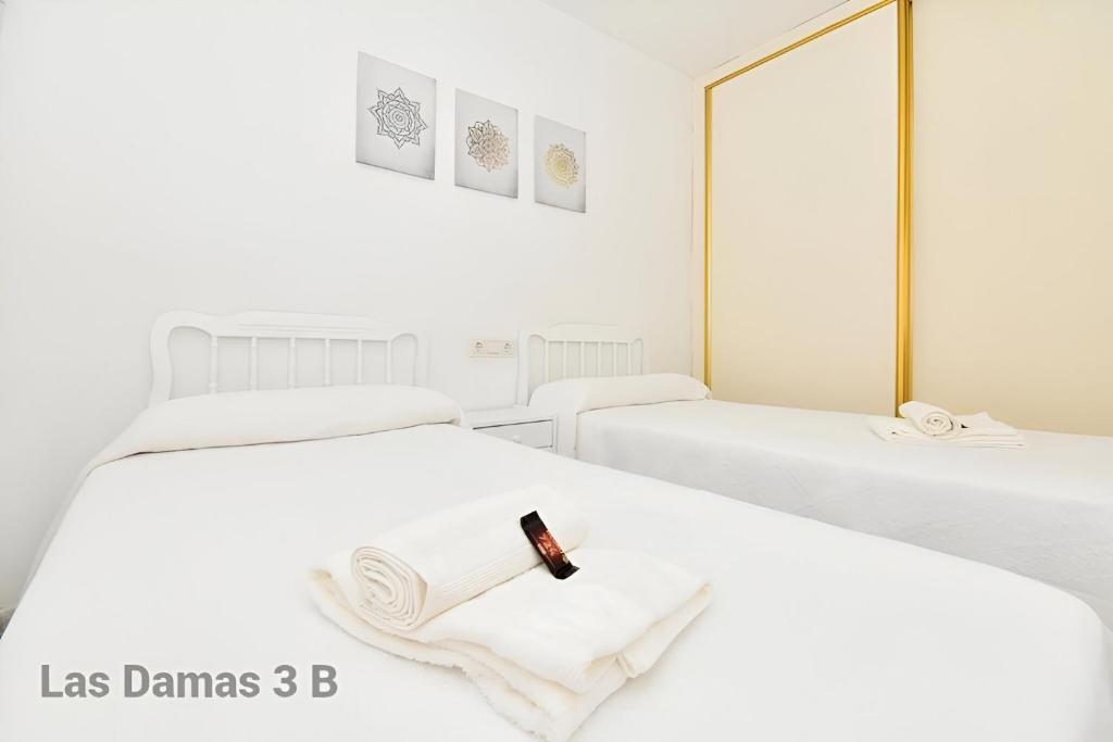a white room with two beds with a candle on them at Las Damas 3B Beach Front - Pool & Parking in Benidorm