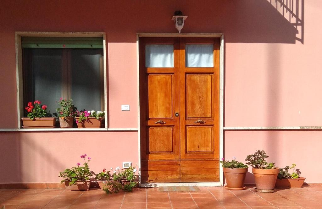 a house with a wooden door and potted plants at La mia casa rosa in Rosignano Marittimo