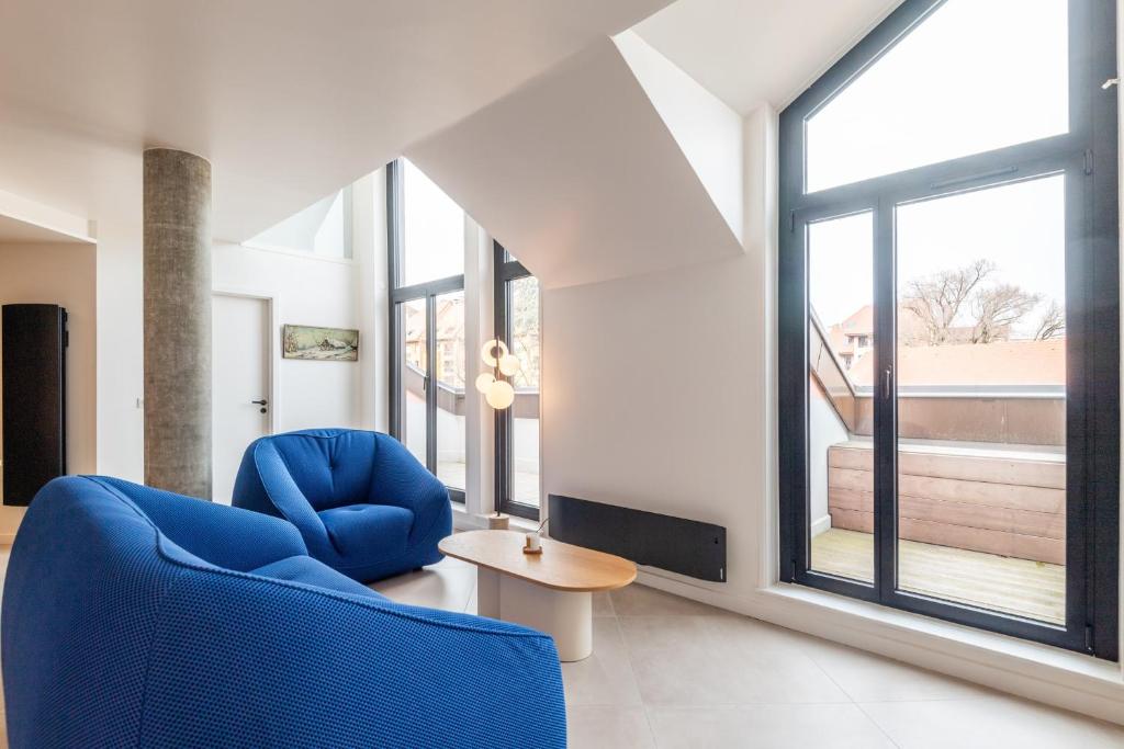 a living room with a blue chair and a table at LA MANUFACTURE - Bel Appartement Contemporain en Coeur de ville in Annecy