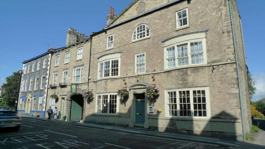 ein altes Steingebäude in einer Stadtstraße in der Unterkunft Orchard Club - Newton House in Knaresborough