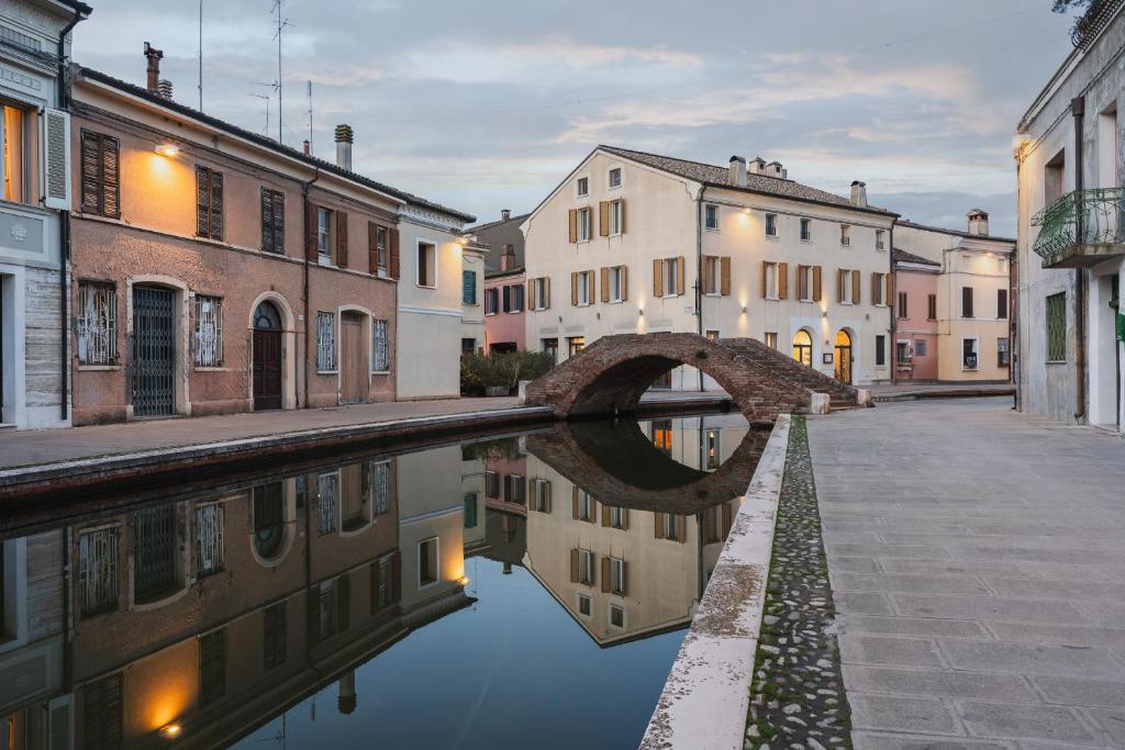 a canal in a city with buildings and a bridge at Al Ponticello in Comacchio