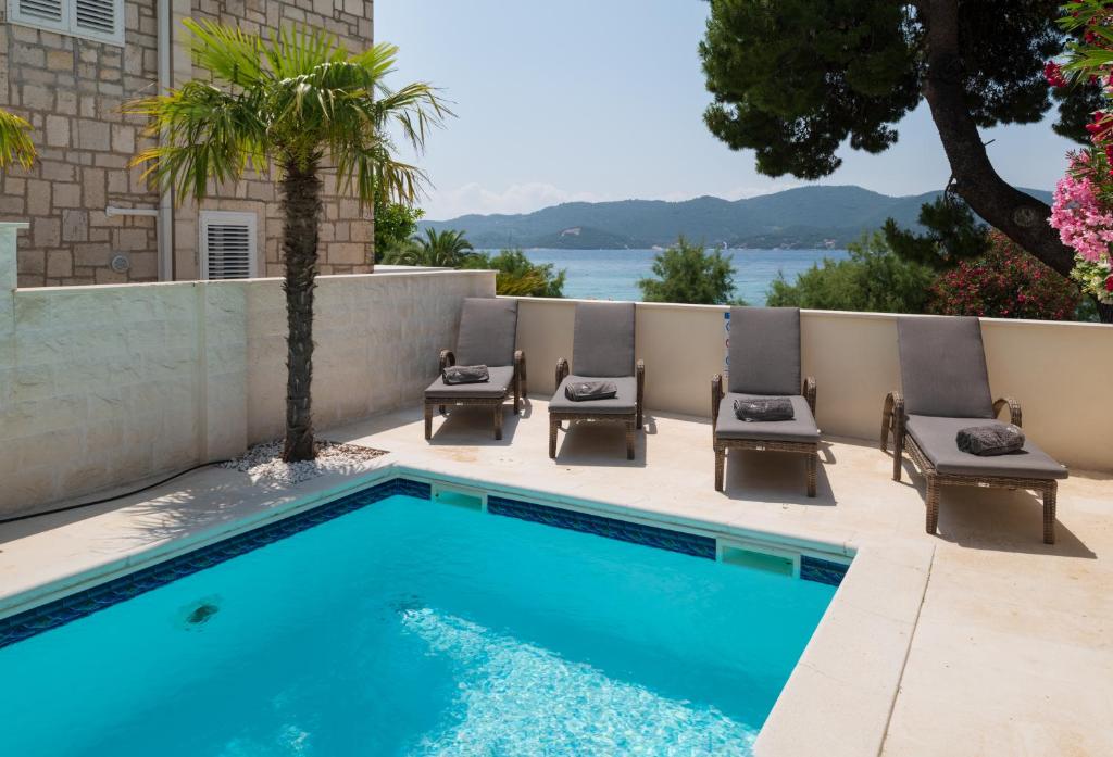 a pool with four chairs and a palm tree at Villa Suartini Viganj Pool or Jakuzzi in Viganj