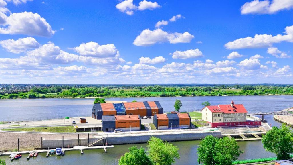 een gebouw naast een rivier met een brug bij Marina Grudziądz in Grudziądz
