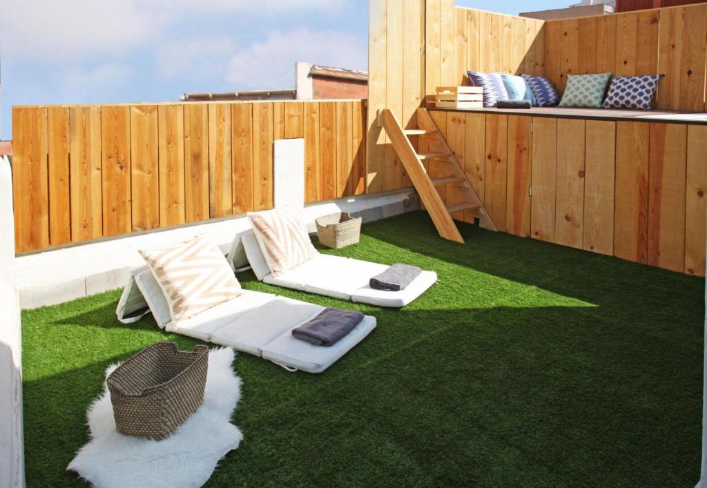 un patio con césped verde y una valla de madera en Fridays Flats Casa Lemonade, en Hospitalet de Llobregat