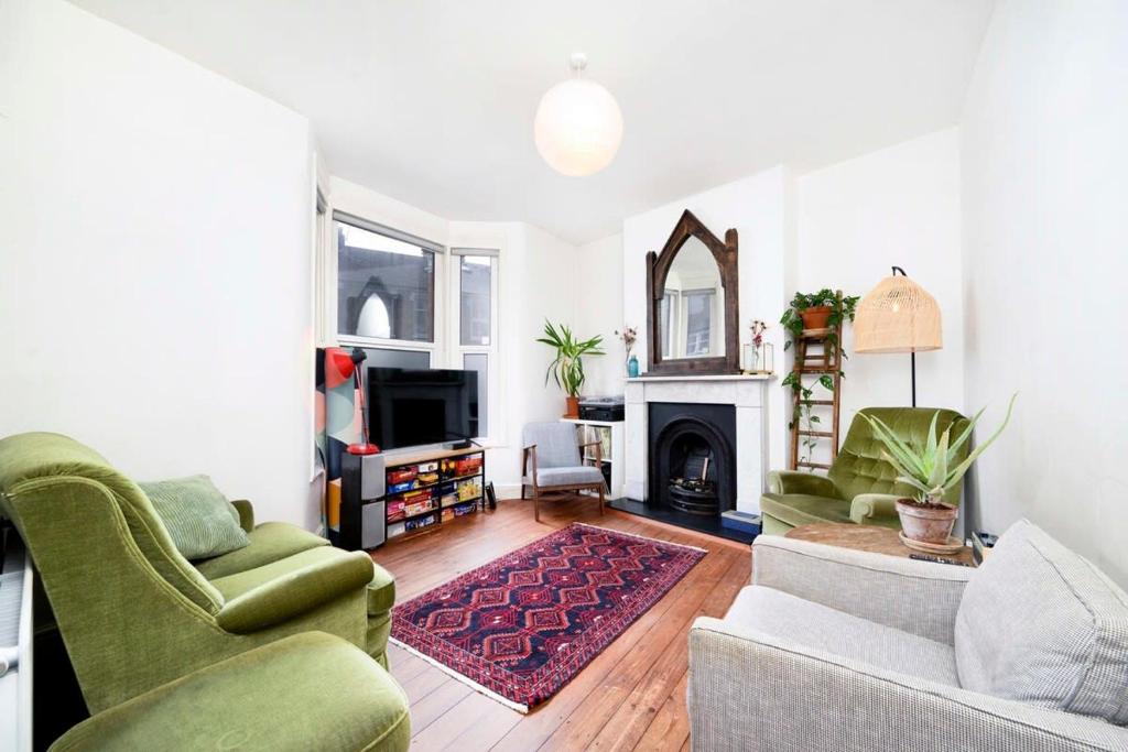 uma sala de estar com duas cadeiras e uma lareira em Charming 3BR Family-Friendly London Home em Londres