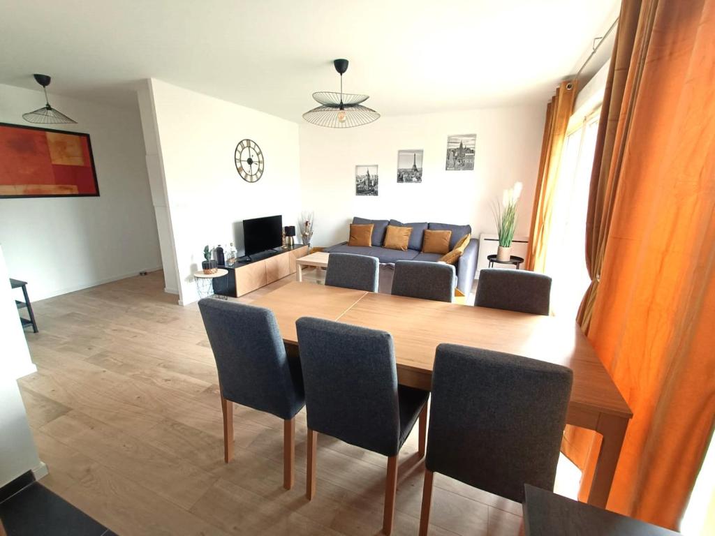 uma sala de jantar e sala de estar com mesa e cadeiras em Les vergers de Serris, 6 personnes, 2 PK privés, balcon, lit bébé em Serris