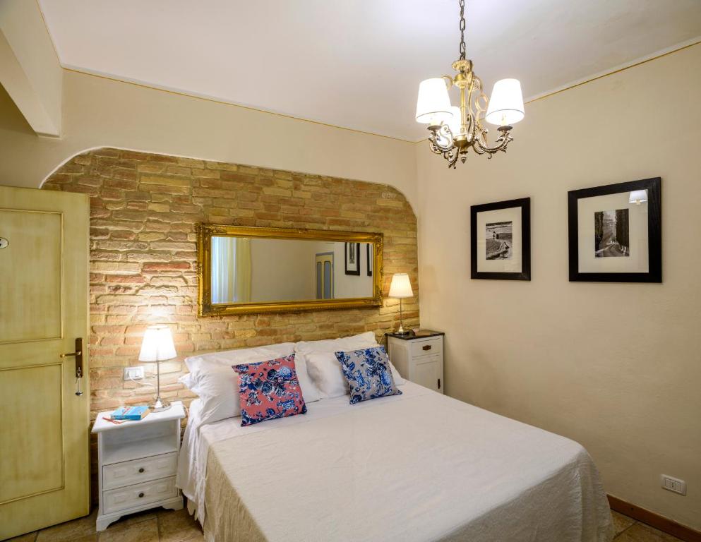 een slaapkamer met een bed met een spiegel aan de muur bij Donna Nobile in San Gimignano