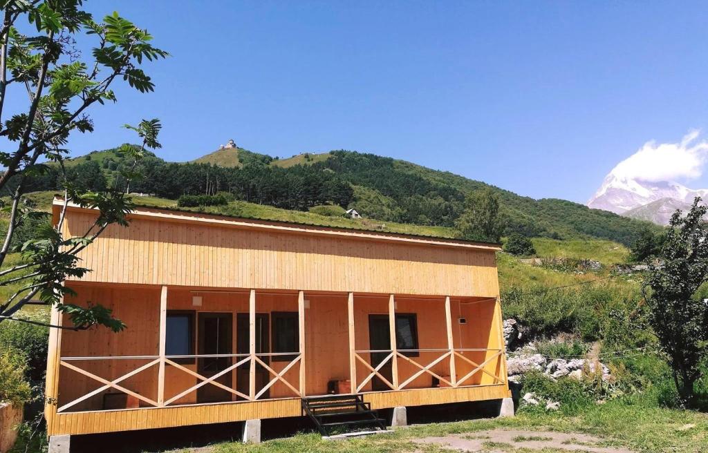 une maison sur une colline avec des montagnes en arrière-plan dans l'établissement Family Hostel Nika, à Kazbegi