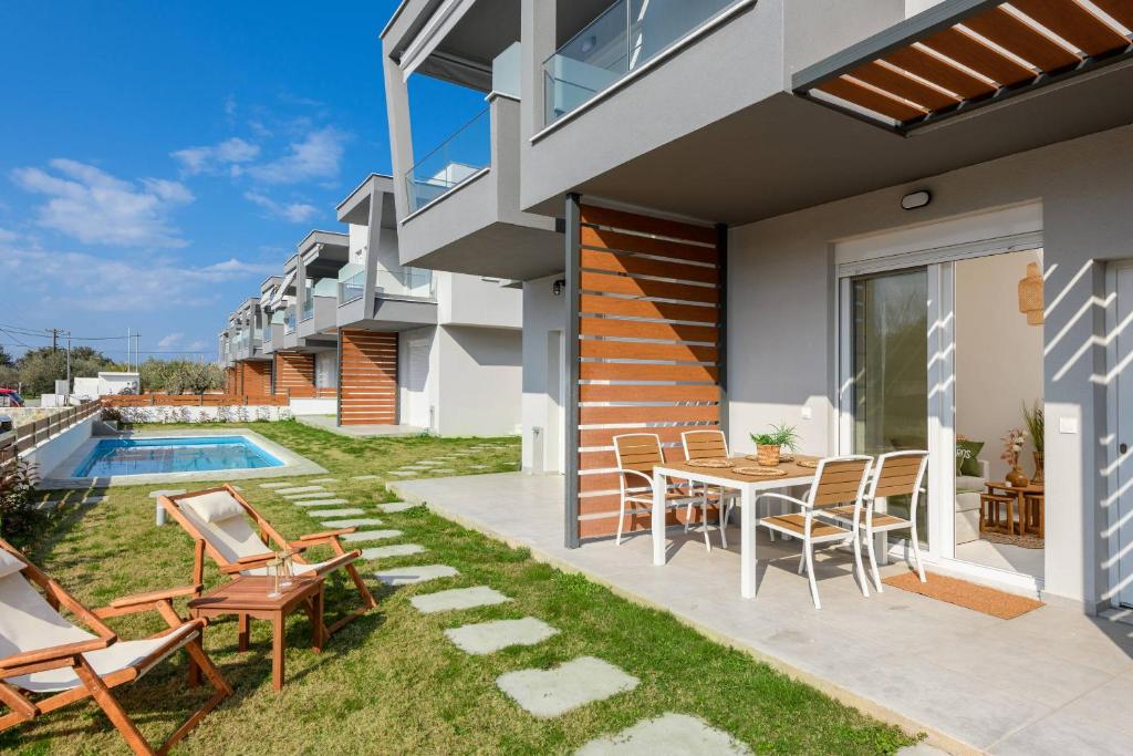 a patio with a table and chairs next to a house at Zefyros Apartments in Skala Rachoniou