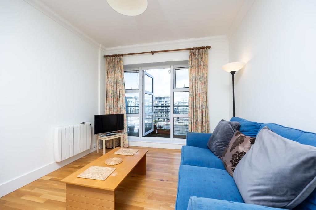 a living room with a blue couch and a tv at Flat w/ Balcony & Canal view - 4min to station in Dublin
