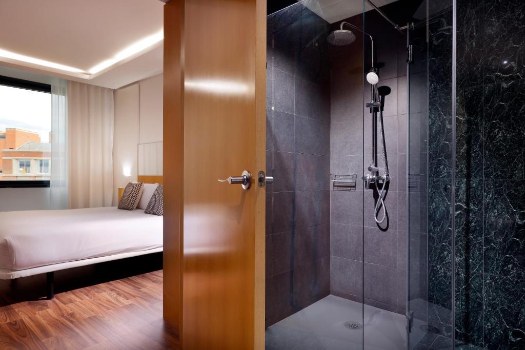 a bathroom with a shower and a bedroom with a bed at Hotel SB Icaria in Barcelona