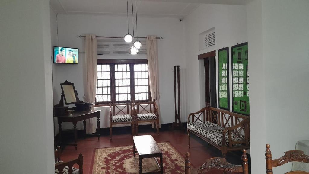 a living room with chairs and a table and windows at Rajavilla in Haputale