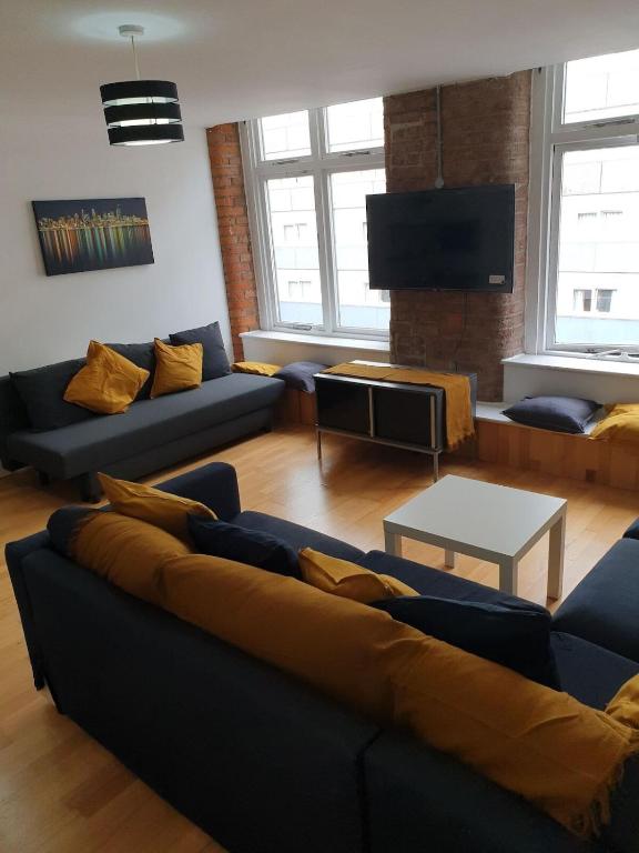 a living room with blue couches and a tv at Fab Manchester City new one bed apartment in Manchester