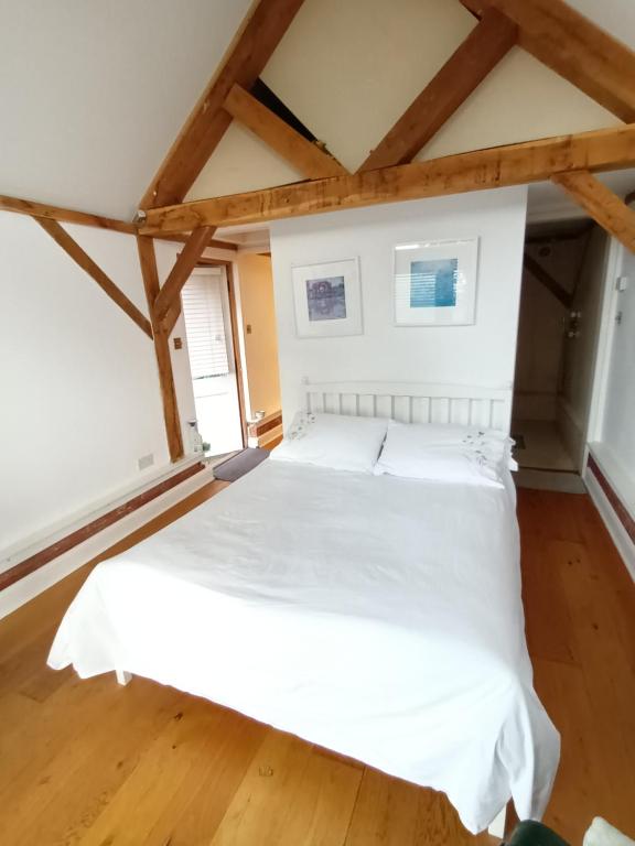 een slaapkamer met een wit bed in een kamer met houten vloeren bij LITTLE OAK - Kingsize Double Oak Studio - Sleeps 2 - Quirky - Rural in Haslemere