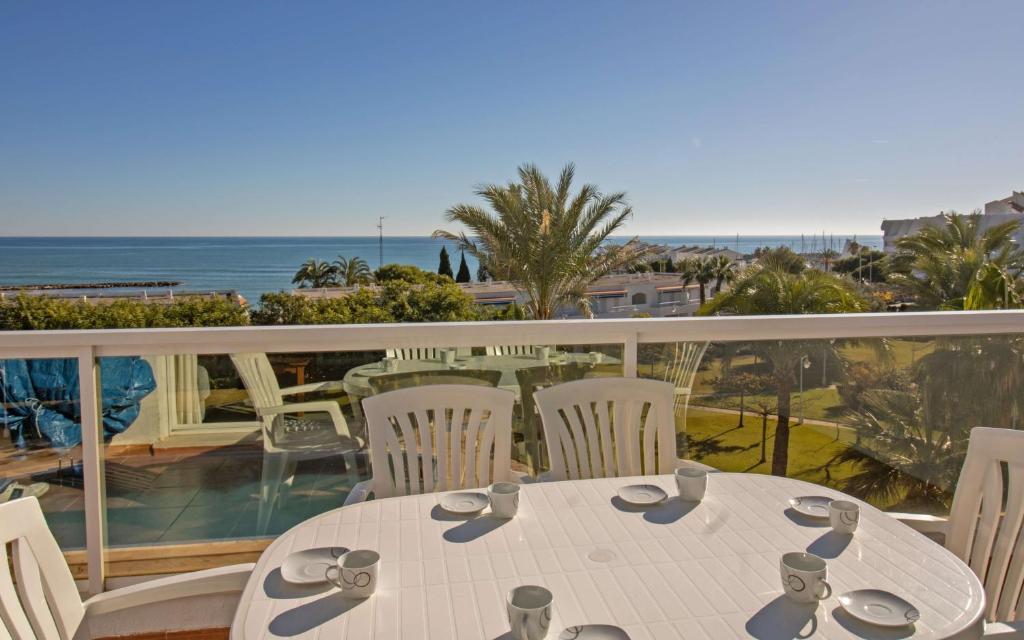 un tavolo bianco e sedie su un balcone con vista sull'oceano di JARDINES DEL PUERTO Primera línea de playa ALBERT VILLAS ad Alcossebre