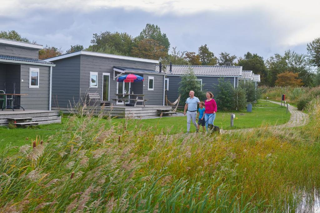 a man and a woman walking in front of a house at Siblu camping Lauwersoog in Lauwersoog