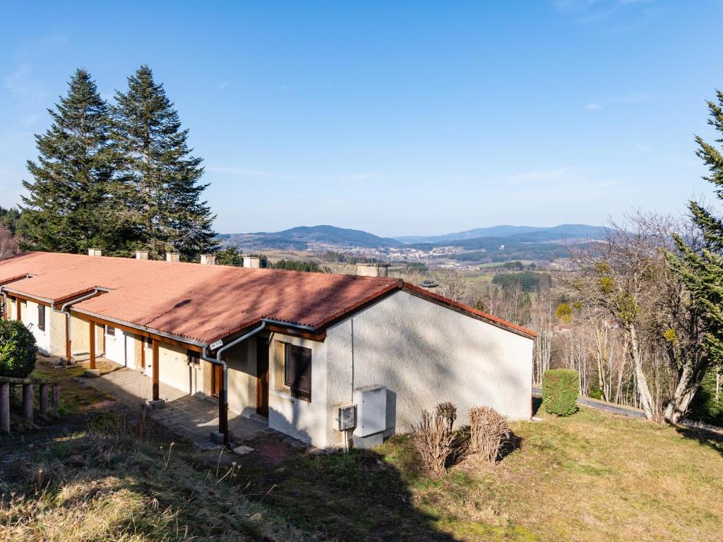 une maison avec un toit métallique sur une colline dans l'établissement Vacancéole - Les Monts du Forez, à Saint-Jean-la-Vêtre
