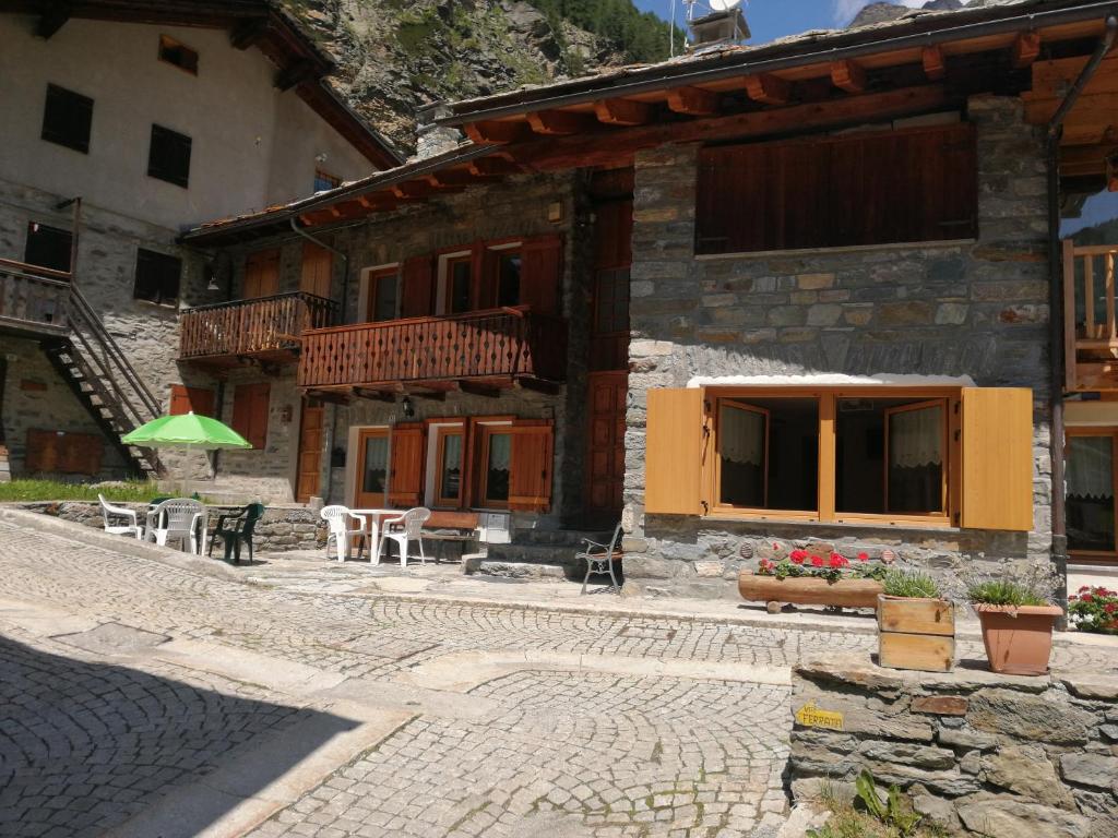 a building with a patio and a table and chairs at Appartamenti Lucianaz in Rhêmes-Notre-Dame