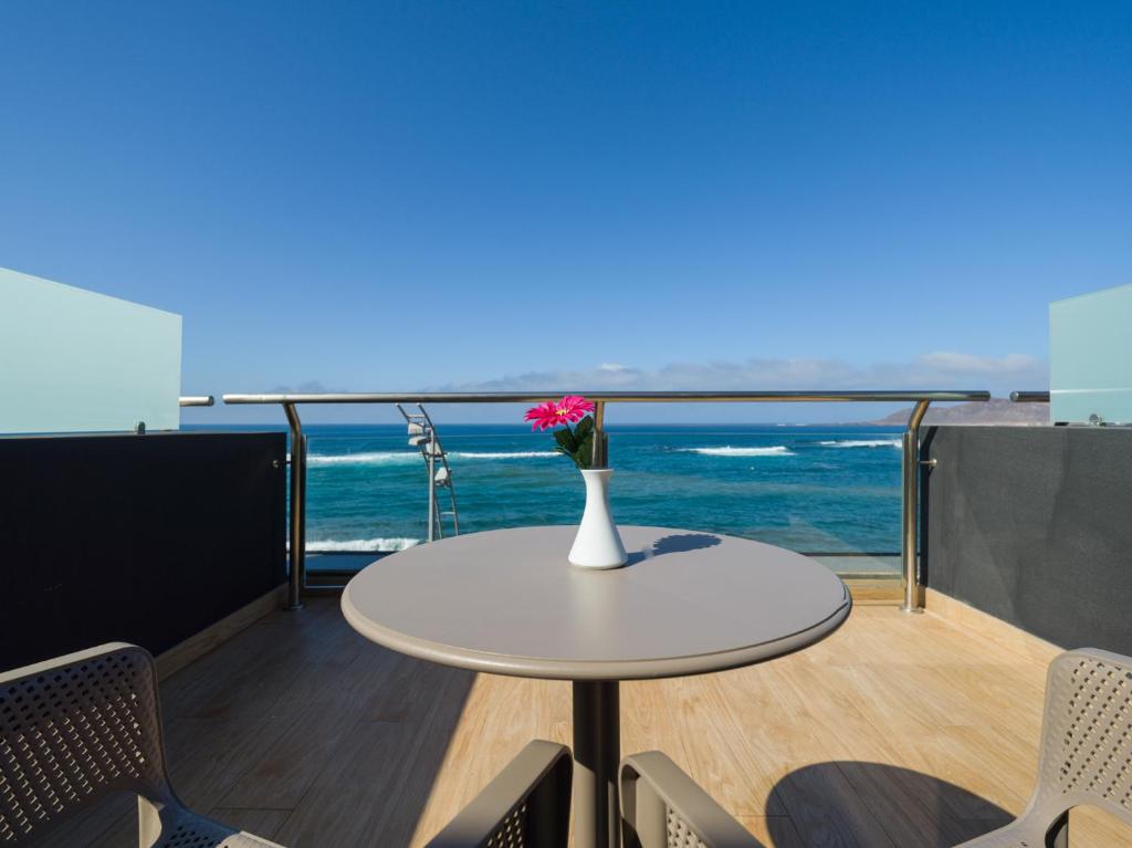 a table with a vase of flowers on a balcony at Sercotel Playa Canteras in Las Palmas de Gran Canaria