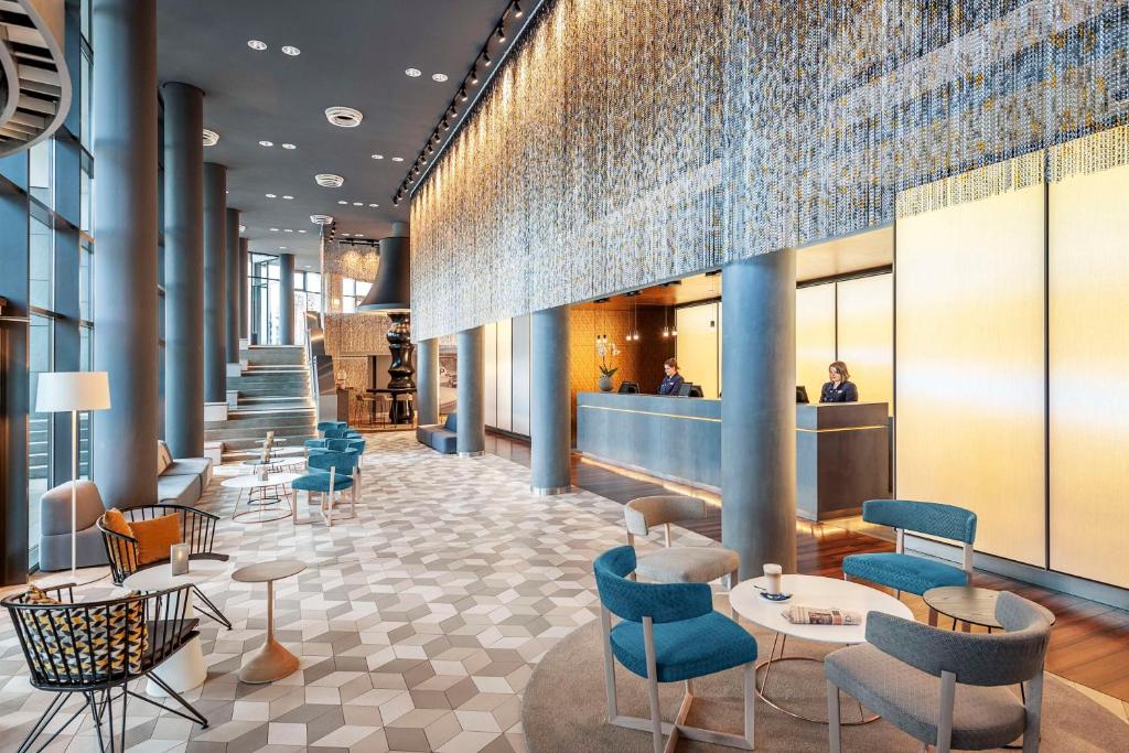 a rendering of a lobby with chairs and tables at NH Berlin Alexanderplatz in Berlin
