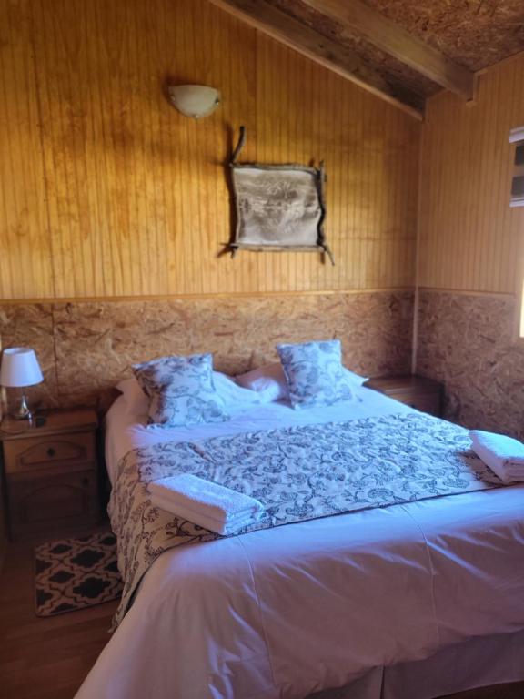 1 dormitorio con 1 cama grande con sábanas azules en Cabañas Vientos del Sur en Puerto Puyuhuapi Aysen, en Puerto Puyuhuapi