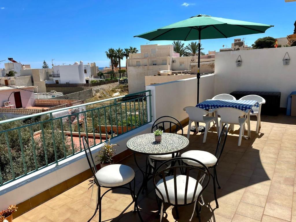 einen Balkon mit Tischen, Stühlen und einem Sonnenschirm in der Unterkunft La terraza de Jimena in Carboneras