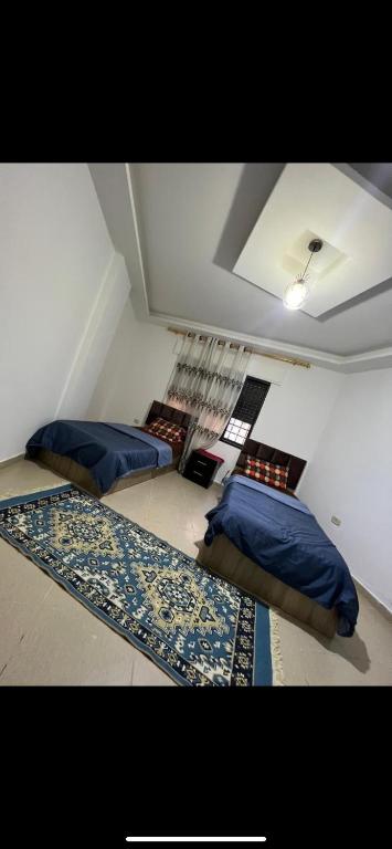 three beds in a room with blue pillows and a rug at rose - 2 bed rooms aprtment in Amman