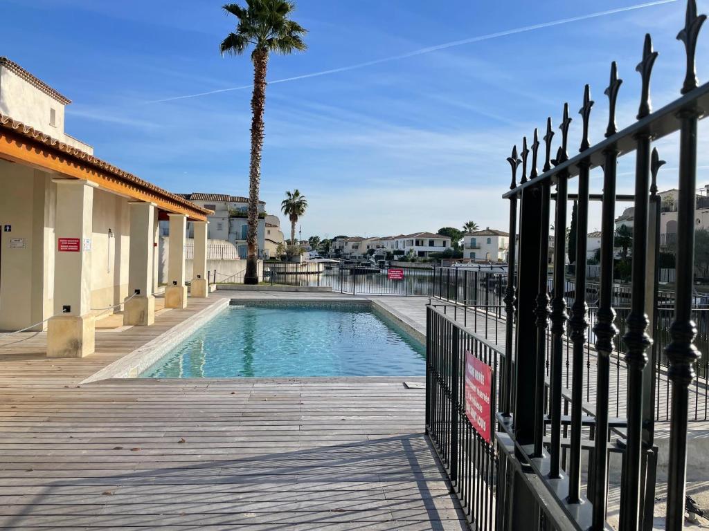 a swimming pool with a fence and a palm tree at Résidence quai St Louis Villa t4 pour 6 personnes N1 47 in Aigues-Mortes