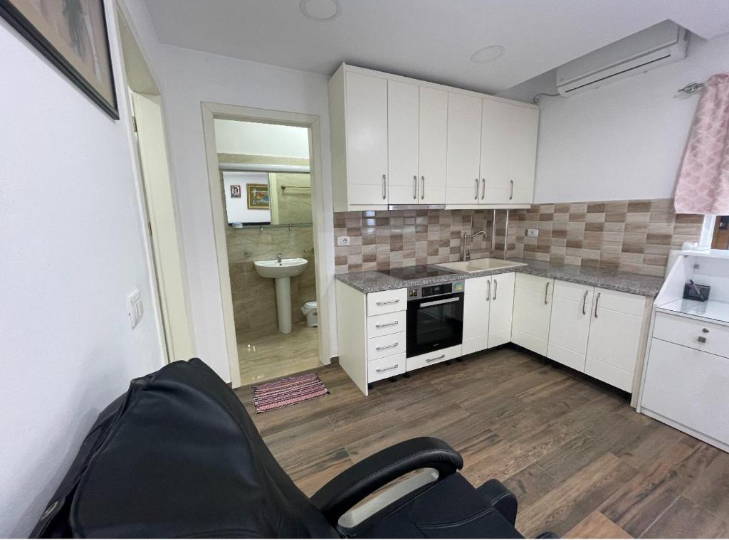 una cocina con armarios blancos y una silla en una habitación en Apartment MDrasa, en Gjirokastra