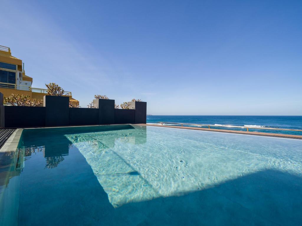 - une piscine avec l'océan en arrière-plan dans l'établissement Sercotel Playa Canteras, à Las Palmas de Gran Canaria