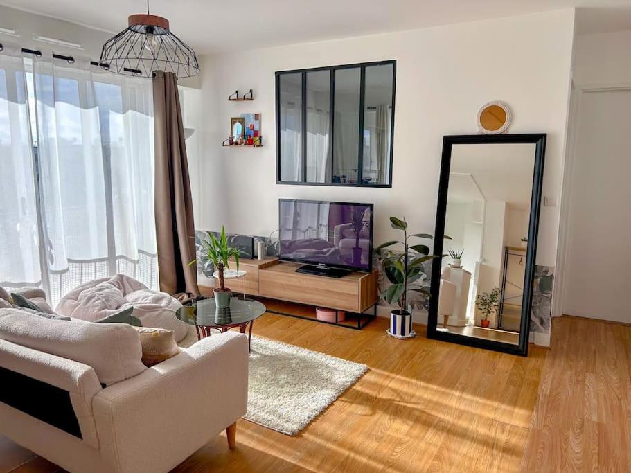 sala de estar con sofá, TV y espejo en Appartement lumineux rénové (proche JO), en Épinay-sur-Seine