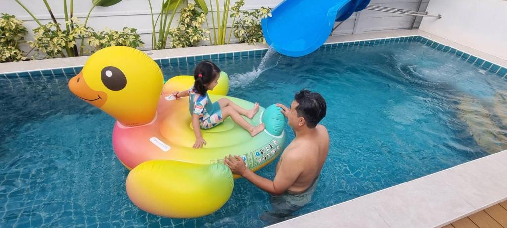 mężczyzna i dwójka dzieci na tratwie w basenie w obiekcie อิมอิม เฮ้าส์ พูลวิลล่า อุดรธานี w mieście Udon Thani