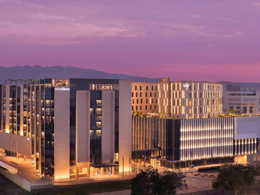 a group of buildings in a city at night at Mövenpick Hotel & Apartments Ghala Muscat in Muscat