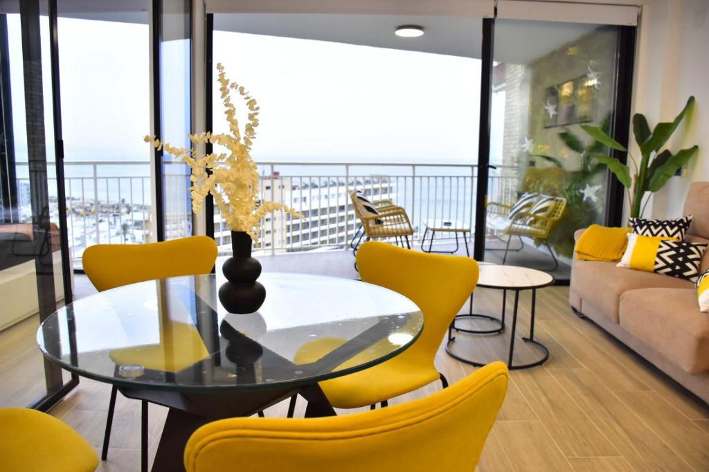 ein Wohnzimmer mit einem Glastisch und gelben Stühlen in der Unterkunft Apartamento Calma Las Conchas in Torremolinos