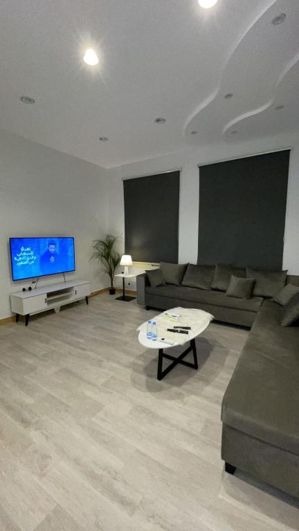 sala de estar con sofá y TV en فندق أسرار العلا الفندقية, en Al Ula