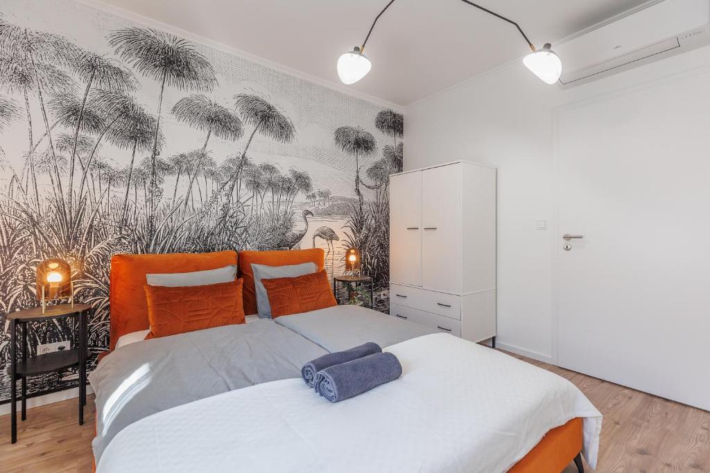 1 dormitorio con 1 cama con almohadas de naranja y palmeras en D26 Luxury Suites, en Budapest