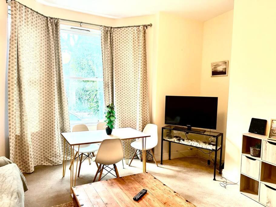 sala de estar con mesa y TV en Peaceful park side apartment en Hastings