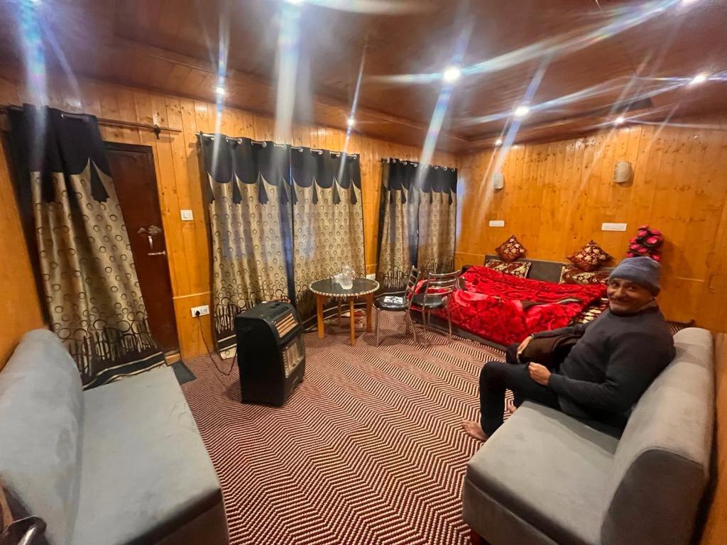 Sheraz palace في Tangmarg: رجل يجلس على أريكة في غرفة المعيشة