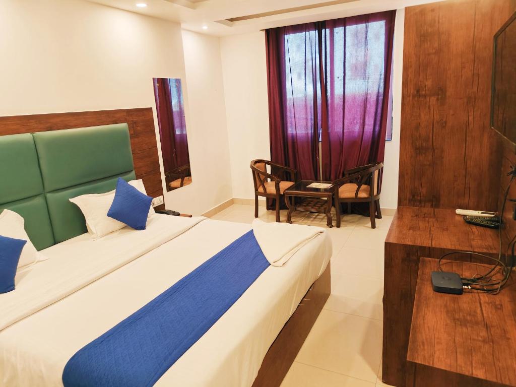 Hotel Tej Plaza Near IGI Airport في نيودلهي: غرفة نوم بسرير وكرسي ونافذة