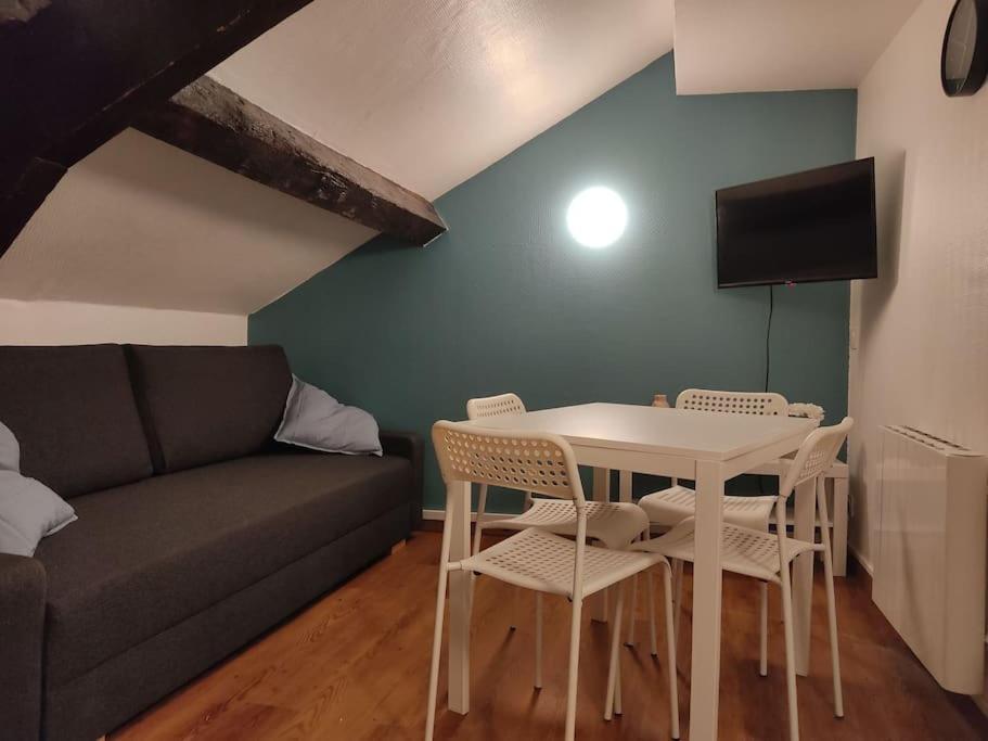 uma sala de estar com um sofá, uma mesa e cadeiras em Studio Rémois - WIFI/Netflix em Reims