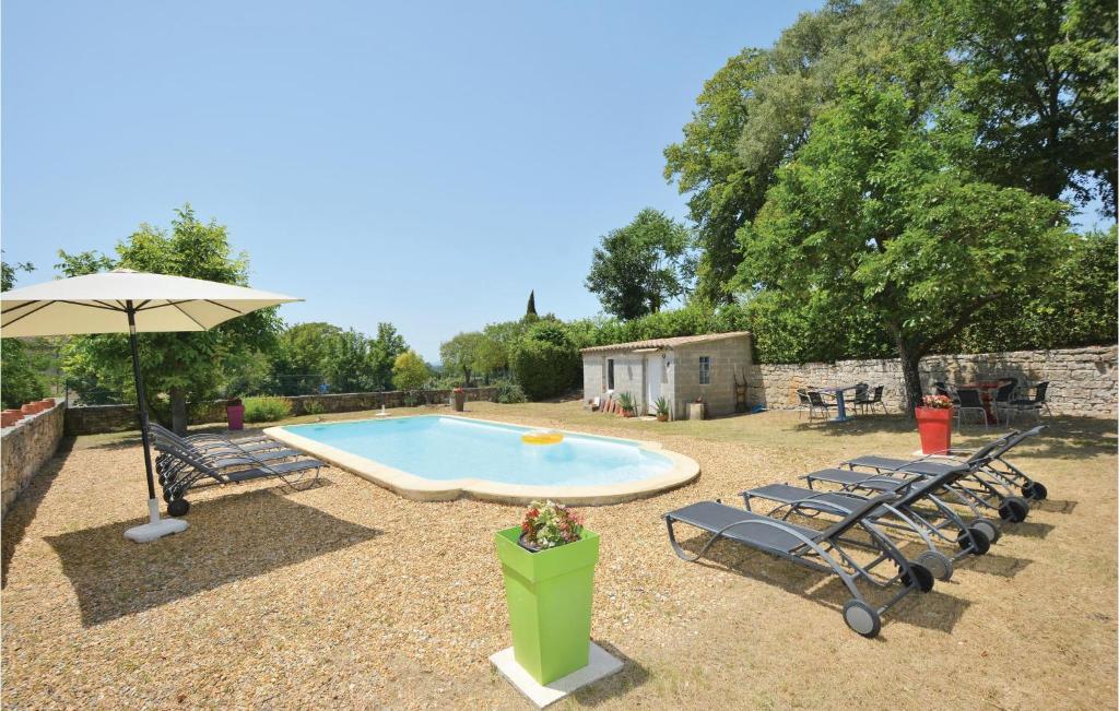 a swimming pool with two chairs and an umbrella at Amazing Home In Barjac With 3 Bedrooms, Wifi And Outdoor Swimming Pool in Barjac