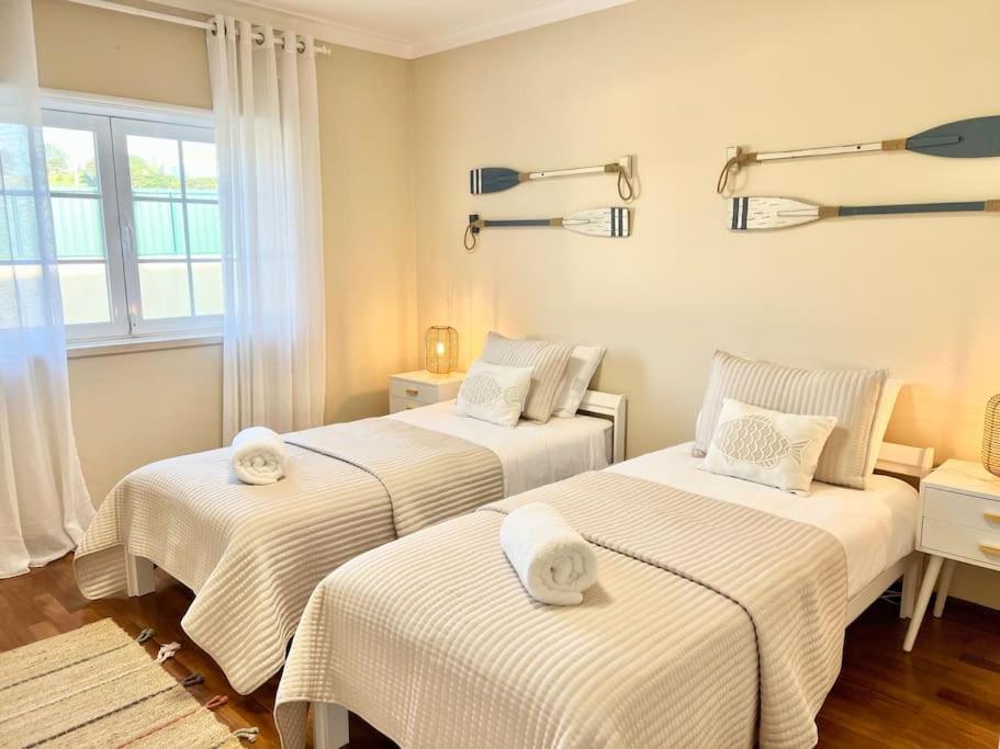 um quarto com 3 camas e lençóis brancos em Antonio's Captain House close to beaches em Atouguia da Baleia