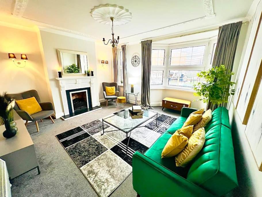 uma sala de estar com um sofá verde e uma lareira em Meadows Court -Wyndale- Central Mansion Style 3BR em Birmingham