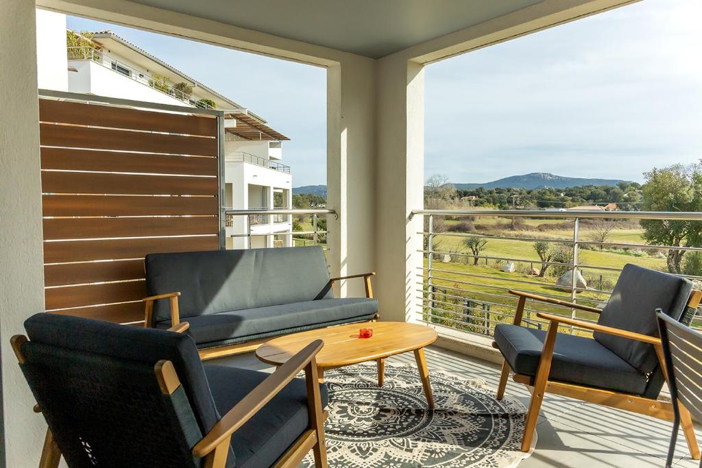 d'un balcon avec des chaises, une table et une grande fenêtre. dans l'établissement Flaubert 16 - Domaine d'Arca - 4 pers - étage 1, à Porto-Vecchio