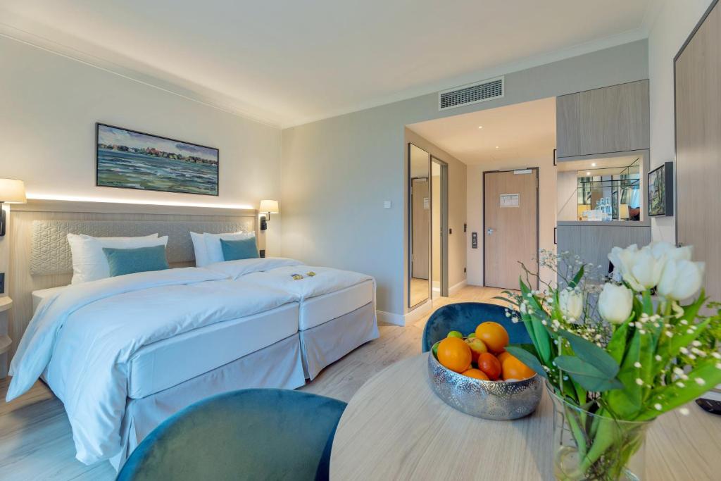 a hotel room with a bed and a bowl of fruit on a table at Seehotel Zarrentin in Zarrentin