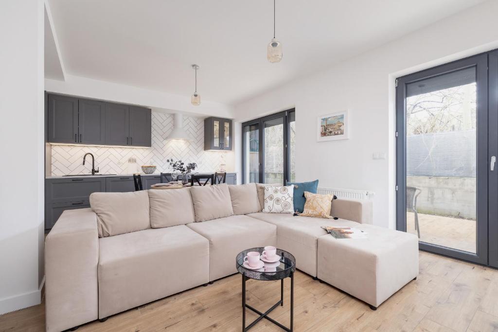 a white living room with a white couch and a kitchen at Apartment in Krakow with parking and balcony by Renters in Modlnica