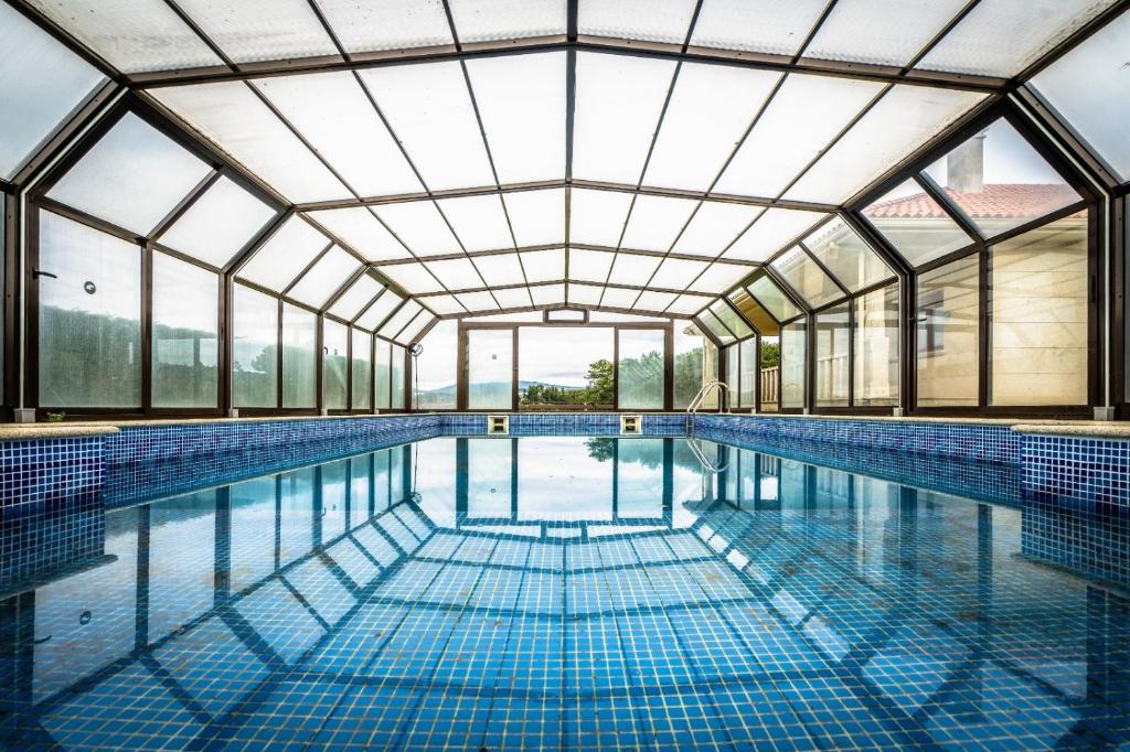 una piscina cubierta con un gran techo de cristal en casa de lujo con pisicina y jardin en el rural en Meis