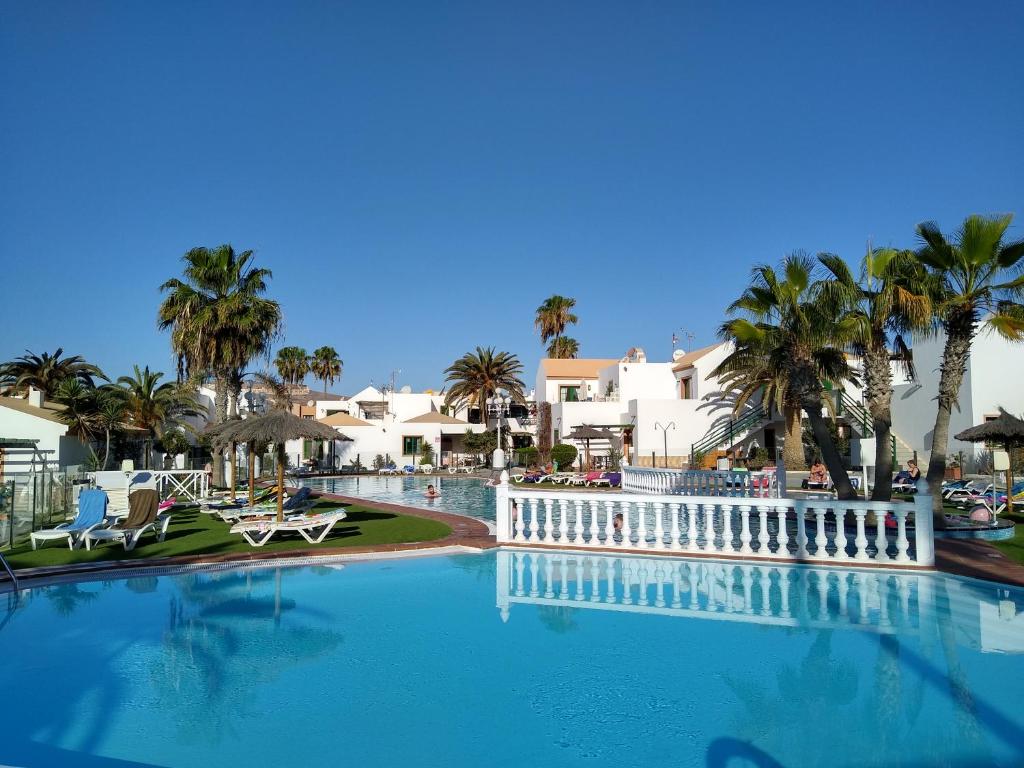 a large swimming pool with palm trees and houses at Puerta del Sol in Caleta De Fuste